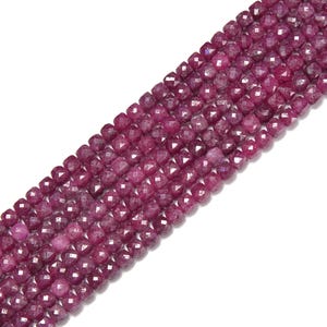 May include: Strands of faceted, deep red gemstone beads. The beads are square-shaped and have a sparkling, polished finish. The beads are strung together, creating a continuous line of color and texture. Ideal for jewelry making.