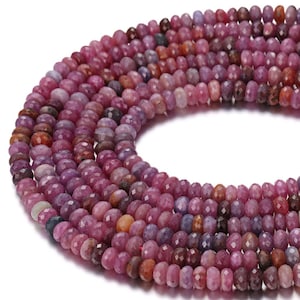May include: Strands of faceted ruby beads in shades of pink, purple, and red. The beads are small and round, with a polished, reflective surface. The beads are strung together, forming a necklace or bracelet.