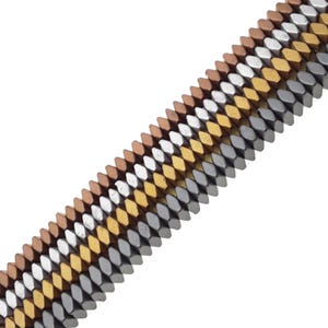 May include: A diagonal view of a bracelet or strand of beads. The beads are small, geometric, and in a variety of metallic colors, including copper, silver, and gold. The beads are arranged in parallel rows, creating a textured surface.