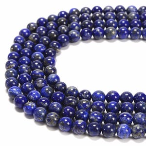 May include: A strand of round, dark blue lapis lazuli beads with gold flecks. The beads are strung on a clear thread and are arranged in a circular pattern.