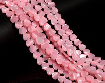 May include: A strand of pink heart-shaped beads made from mother of pearl. The beads are strung on a clear thread and are arranged in a staggered pattern.
