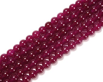 May include: Strands of deep burgundy-colored, round gemstone beads. The beads have a polished, glossy finish and are strung together, creating a flowing, diagonal pattern against a white background. These beads are suitable for jewelry making.