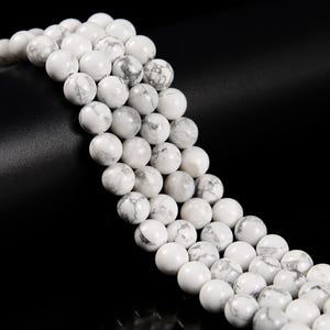 May include: Strands of white Howlite gemstone beads with gray marbling. The round beads are strung together, creating a natural and elegant look. Ideal for jewelry making or crafting projects.