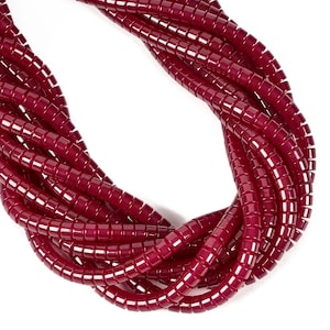 May include: A multi-strand necklace composed of numerous deep burgundy, cylindrical beads. The beads are arranged in a dense, overlapping cluster, creating a continuous, curved shape with a glossy, uniform finish throughout the entire piece.