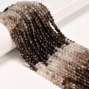 May include: Strands of faceted beads in varying shades of brown and clear. The beads are small and round, with a sparkling, polished finish. The beads are arranged in a cascading pattern, creating a visually appealing display.