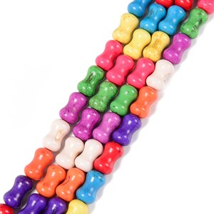 May include: Rows of colorful, bone-shaped beads in various shades including red, purple, green, yellow, and blue. The beads are strung together, creating a vibrant and textured pattern. Ideal for jewelry making or craft projects.