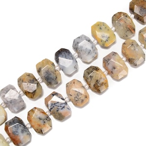 May include: Strands of faceted gemstone beads in shades of tan, gray, and yellow. The beads have a geometric shape and are strung together with small, clear beads. The gemstones have a natural, speckled appearance, and are set against a white background.