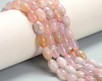 May include: Strands of oval-shaped beads in shades of pink, peach, and white. The beads are strung on a bright pink cord. The beads have a polished, translucent appearance, suggesting they are made of stone or glass. The beads are likely for jewelry making.