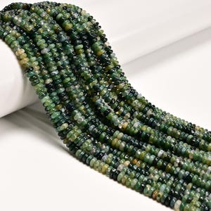 May include: Strands of green moss agate beads. The beads are small, round, and have a mix of dark and light green colors with some white and yellow inclusions. The beads are strung together, creating a flowing, textured appearance. Ideal for jewelry making.