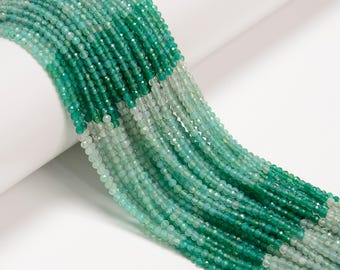 May include: Strands of faceted beads in shades of green, from deep emerald to pale seafoam. The beads are small and round, with a sparkling, polished finish. The strands are arranged in a flowing, cascading pattern, suggesting jewelry making supplies.