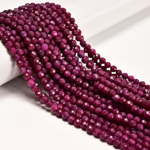 May include: A collection of multiple strands of deep magenta, faceted round beads. Each bead features a textured, multi-faceted surface that reflects light, creating a consistent, uniform appearance across the entire length of the strands.