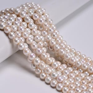 May include: Strands of lustrous, creamy white pearls. The pearls are round and evenly sized, with a subtle iridescent sheen. The image showcases multiple strands, suggesting they are ready for jewelry making or display.
