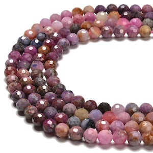 May include: Strands of faceted gemstone beads in shades of pink, purple, and brown. The beads are round and have a polished, reflective surface. The gemstones are strung together, creating a necklace or bracelet.
