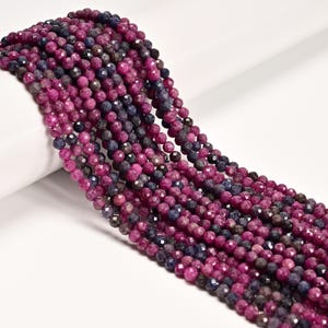 May include: Strands of faceted gemstone beads in shades of deep magenta, dark blue, and gray. The beads are small and round, with a sparkling, polished finish. The beads are strung together, creating a flowing, textured appearance. Ideal for jewelry making.