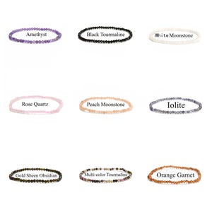 May include: Nine different gemstone bracelets, each with a different color and type of stone. The bracelets are arranged in three rows of three, with the names of the stones printed below each bracelet. The stones include amethyst, black tourmaline, white moonstone, rose quartz, peach moonstone, iolite, gold sheen obsidian, multi-color tourmaline, and orange garnet.