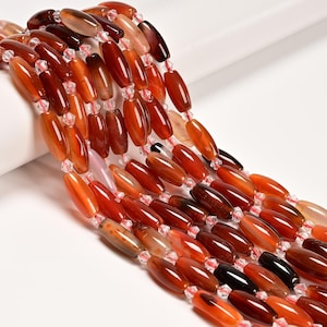 May include: Strands of oval-shaped beads in shades of red, orange, and brown. The beads are strung together with small, clear, faceted beads. The beads have a polished, glossy finish and vary in color intensity.