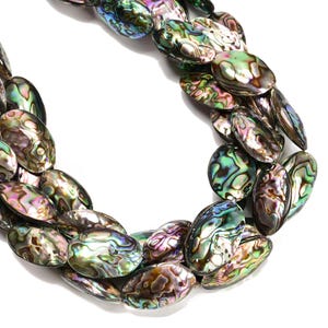May include: A close-up of a necklace made of iridescent abalone shell beads. The oval-shaped beads display a range of colors, including green, blue, purple, and brown, with a shimmering, pearlescent effect. The necklace is set against a white background.