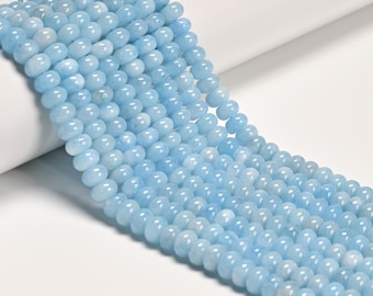 Puede incluir: Un hilo de cuentas redondas y lisas de color azul claro dispuestas en varias filas paralelas. Cada cuenta presenta un color azul cielo pálido consistente con un acabado pulido y semitranslúcido, creando una apariencia uniforme a lo largo de todo el hilo.