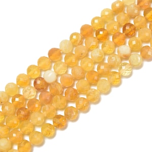 May include: Strands of faceted, round gemstone beads in shades of yellow and orange. The beads have a polished, reflective surface and are strung together, creating a textured and colorful display. Ideal for jewelry making.
