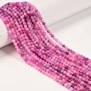 May include: Strands of faceted, round beads in shades of pink and purple. The beads are strung together, creating a flowing, textured appearance. The beads are likely made of a gemstone or glass, and are suitable for jewelry making.