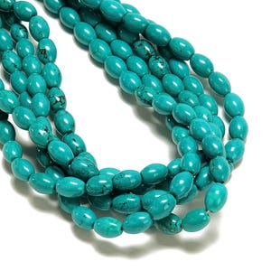 May include: Close-up of several strands of turquoise-colored oval beads. The beads have a polished, glossy finish and are strung together. The beads are a vibrant shade of turquoise with some natural matrix patterns.