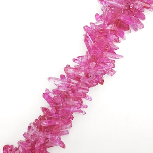 May include: A strand of vibrant pink crystal quartz beads. The crystals are clustered together, creating a textured, irregular line against a white background. The crystals have a translucent quality, with varying shades of pink.