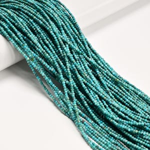 May include: A large collection of small, round turquoise-colored beads strung on multiple thin threads. The beads feature a mottled pattern with varying shades of teal, blue, and dark green, creating a textured appearance across the strands.