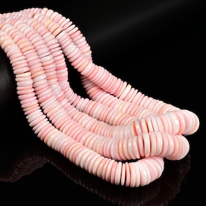 May include: Multiple strands of pale pink, disc-shaped beads arranged in a cascading formation. Each bead features a smooth, rounded edge and a flat profile, creating a uniform, repetitive pattern across the length of the strands.