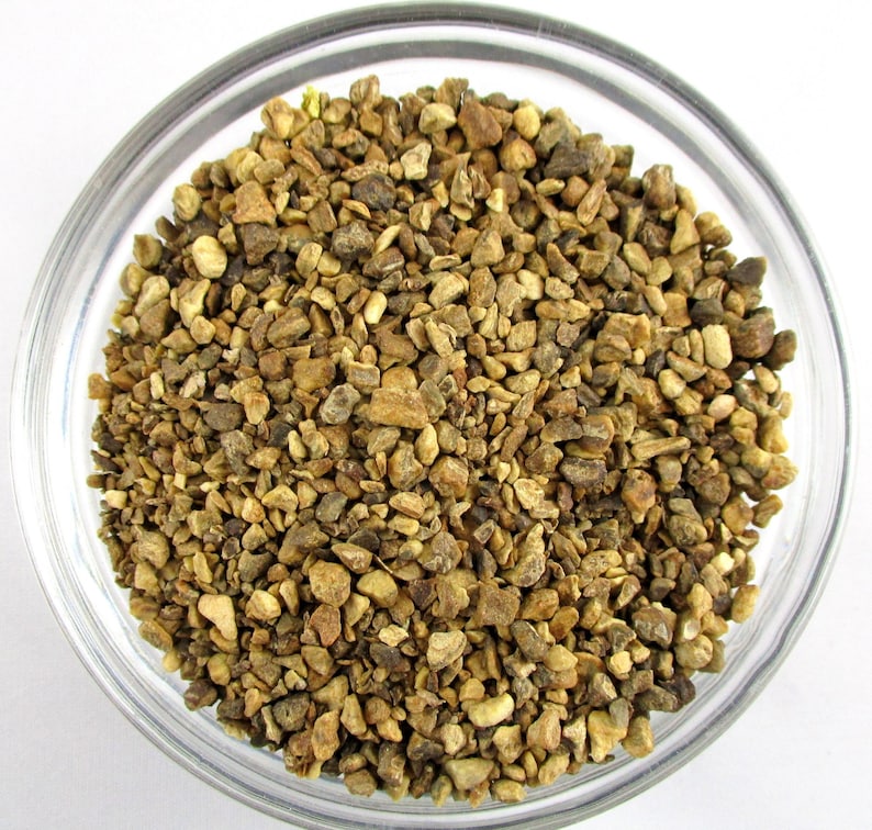 May include: A close-up view of a bowl filled with dried ginger pieces. The ginger pieces are a light brown color and have a rough texture.