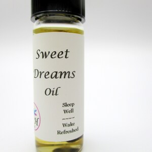 Op de afbeelding: Een klein glazen flesje met een wit etiket waarop "Sweet Dreams Oil" staat. Het etiket bevat ook de tekst "Sleep Well" en "Wake Refreshed".