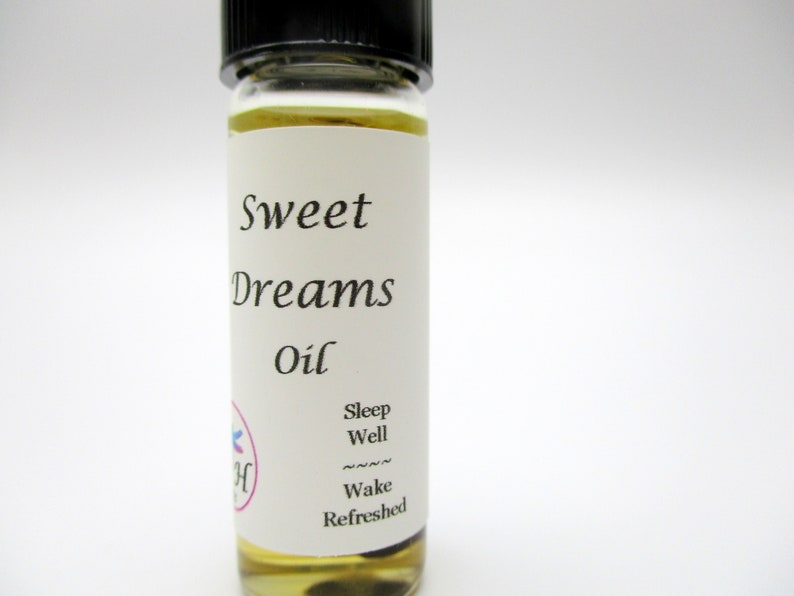 Op de afbeelding: Een klein glazen flesje met een wit etiket waarop "Sweet Dreams Oil" staat. Het etiket bevat ook de tekst "Sleep Well" en "Wake Refreshed".