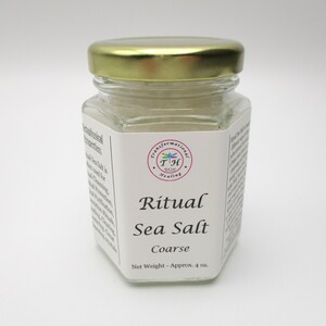 May include: A glass jar with a gold lid filled with white coarse sea salt. The label reads "Ritual Sea Salt Coarse" and "Net Weight - Approx. 4 oz."