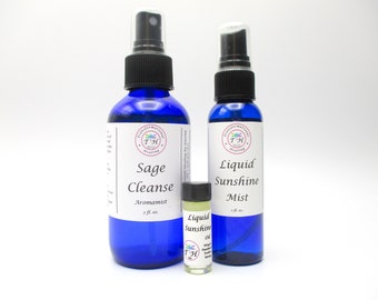 Puede incluir: Tres botellas de vidrio azul con tapas de pulverización y etiquetas. Las botellas están etiquetadas con "Sage Cleanse Aromatist 2 fl. oz.", "Liquid Sunshine Mist 2 fl. oz." y "Liquid Sunshine Oil".
