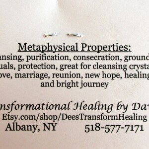 May include: A white card with black text describing the metaphysical properties of a crystal. The text reads: "Metaphysical Properties: Cleansing, purification, consecration, grounding, rituals, protection, great for cleansing crystals, love, marriage, reunion, new hope, healing, and bright journey." The card also includes the text: "Transformational Healing by Dawna Etsy.com/shop/DeesTransformHealing Albany, NY 518-577-7171"