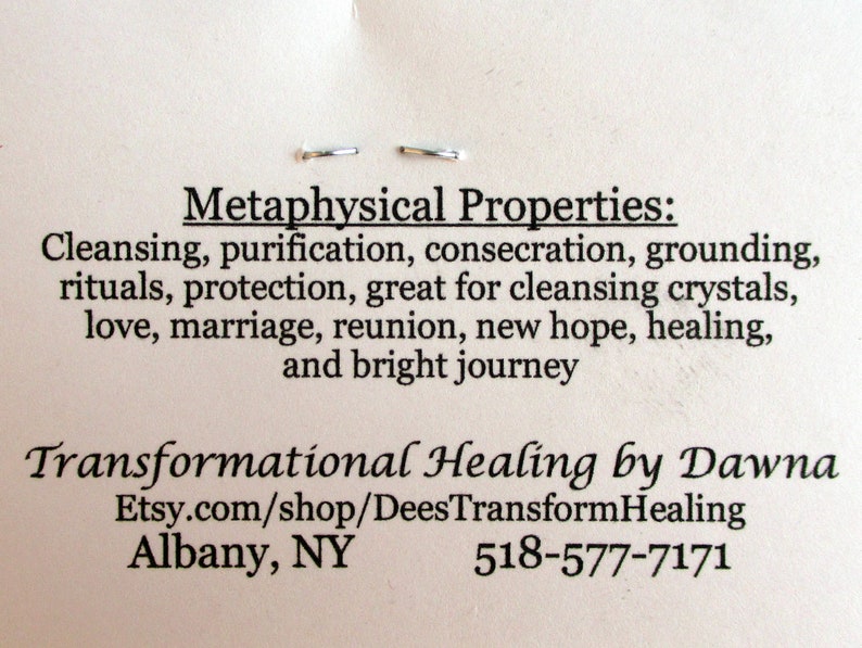 May include: A white card with black text describing the metaphysical properties of a crystal. The text reads: "Metaphysical Properties: Cleansing, purification, consecration, grounding, rituals, protection, great for cleansing crystals, love, marriage, reunion, new hope, healing, and bright journey." The card also includes the text: "Transformational Healing by Dawna Etsy.com/shop/DeesTransformHealing Albany, NY 518-577-7171"