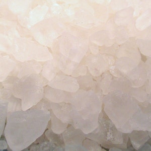 May include: Close-up of a pile of white, opaque, irregularly shaped salt crystals.