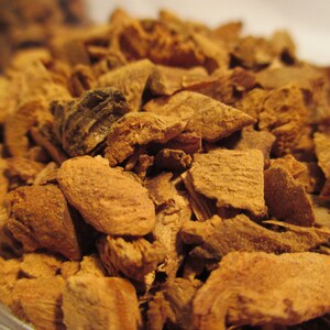 May include: Close-up of a pile of dried, brown, and slightly reddish bark pieces. The bark is broken into irregular shapes and sizes.