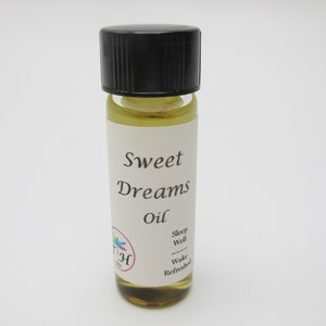 Op de afbeelding: Een klein glazen flesje met een zwarte dop gevuld met een lichtgele vloeistof. Het etiket vermeldt "Sweet Dreams Oil" en heeft een klein libellenlogo. De tekst op het etiket luidt ook "Sleep Well, Wake Refreshed".
