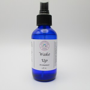 May include: A blue glass bottle with a black spray top. The label reads "Wake Up Aromatist 4 fl. oz."