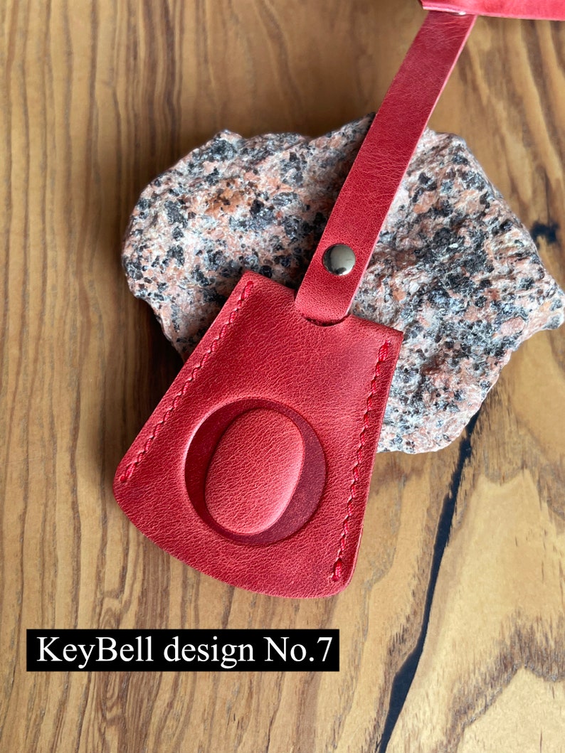 May include: Red leather key fob with a stitched oval design. KeyBell design No. 7.