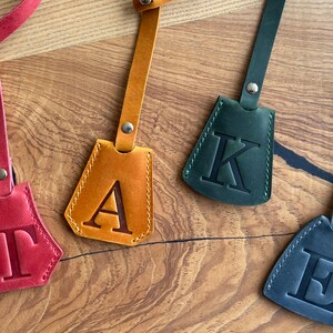 May include: Four leather keychains with different colored leather and a single letter embossed on each. The letters are T, A, K, and E.
