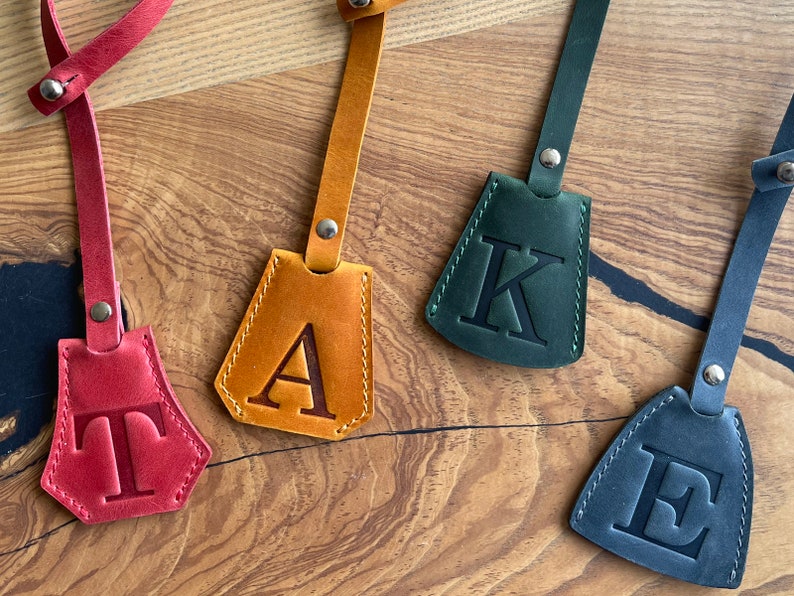May include: Four leather keychains with different colored leather and a single letter embossed on each. The letters are T, A, K, and E.