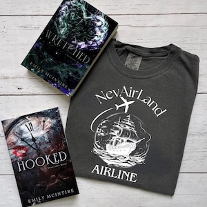 以下が含まれることがあります： 暗い表紙と白い文字の入ったペーパーバックが2冊。本のタイトルは「Wretched」と「Hooked」。著者はエミリー・マッキンタイア。白い文字で「NevAirLand Airline」と書いてあり、円の中に船のグラフィック、その上に飛行機が描かれた濃いグレーのTシャツ。