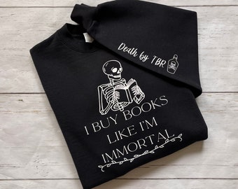 May include: Black sweatshirt with a white skeleton reading a book and the text "I buy books like I'm immortal". The sweatshirt has a matching black hooded top with the text "Death by TBR" and a skull and crossbones.