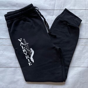 May include: Black sweatpants with a white graphic of a sword and the word "VALKYRIE" on the left leg.
