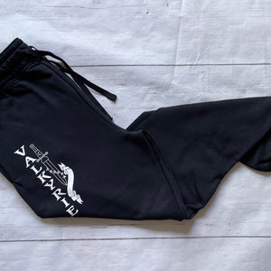 May include: Black sweatpants with a white graphic of a sword and the word "VALKYRIE" on the left leg.
