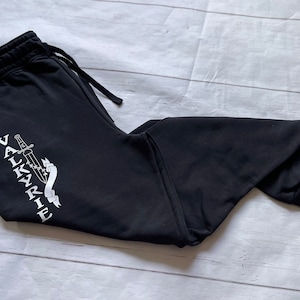 May include: Black sweatpants with a white graphic of a sword and the word "VALKYRIE" on the left leg.