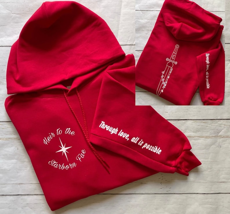 May include: Red hooded sweatshirt with white text and a star design on the front. The text reads "Heir to the Starborn Five". The sleeve has the text "Through love, all is possible".