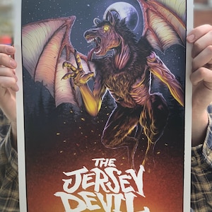 May include: A poster featuring a dark, demonic creature with wings and glowing eyes. The creature is depicted in a fiery, night sky with a full moon. The text "THE JERSEY DEVIL" is written in white, stylized lettering at the bottom of the poster.