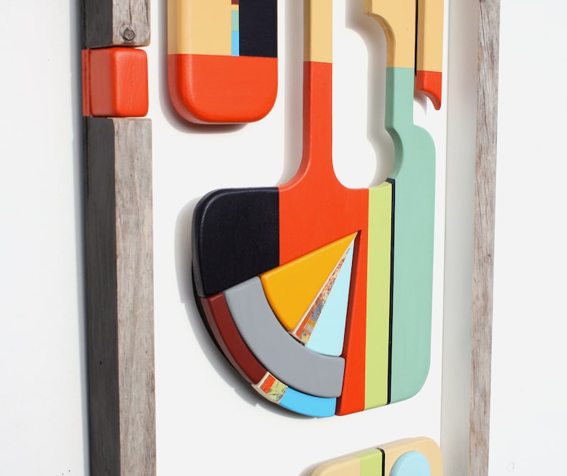 Puede incluir: Una pieza de arte de pared geom&eacute;trico abstracto enmarcado con una variedad de colores, incluyendo rojo, naranja, amarillo, verde, azul y negro. La pieza est&aacute; hecha de madera y tiene un aspecto r&uacute;stico y hecho a mano.